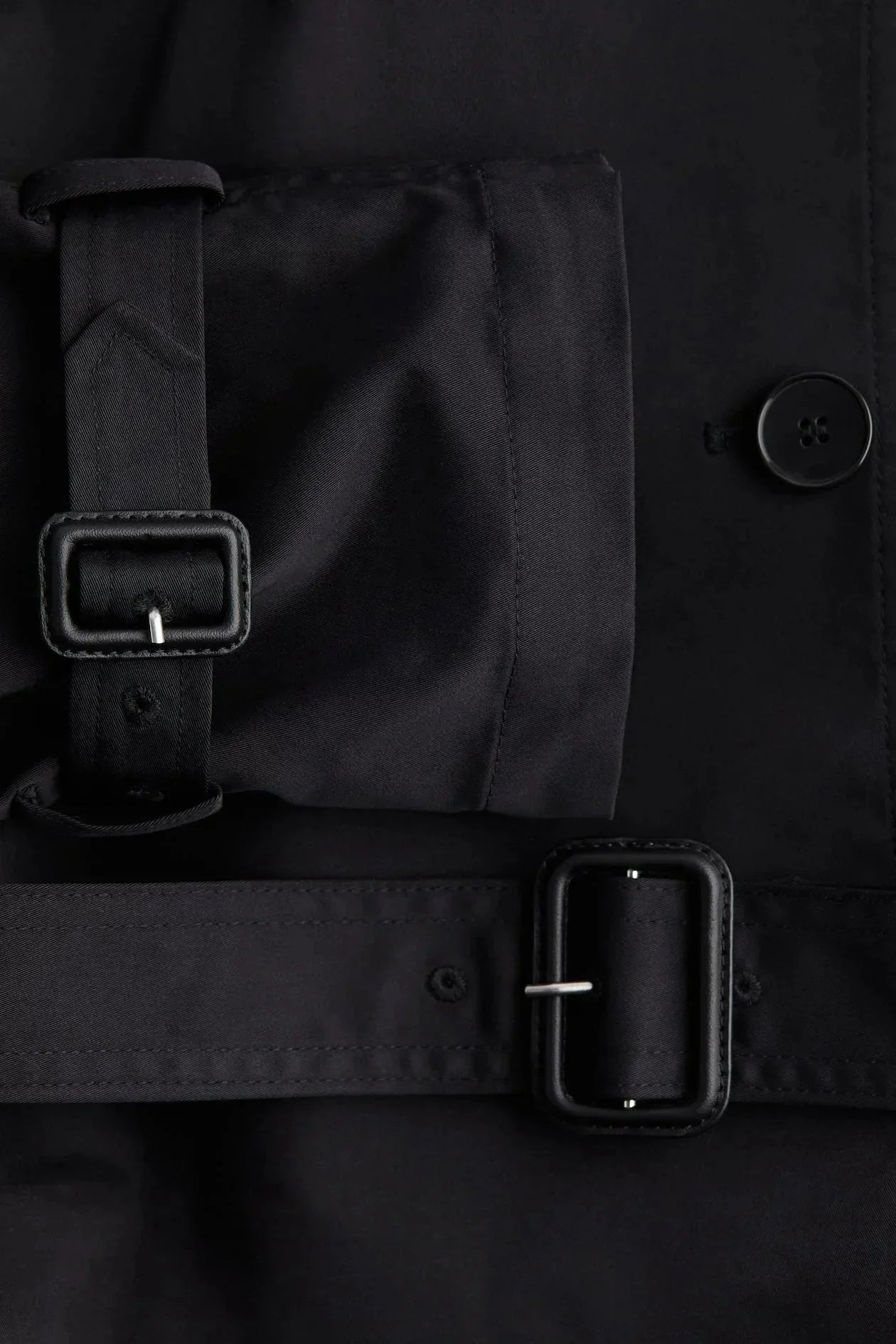 Black trench coat belt detail with stand-up collar and buttoned front