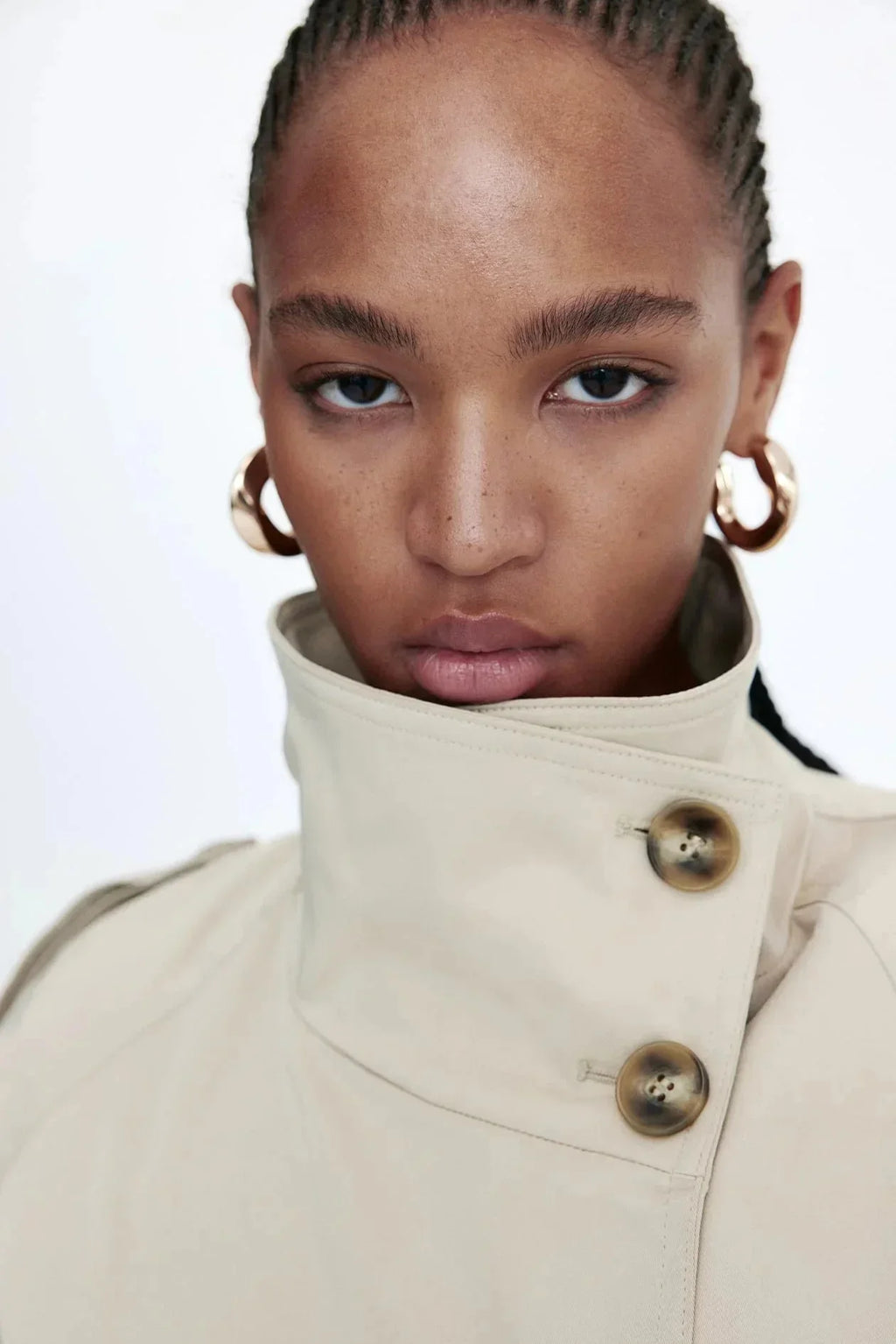 Light beige stand-collar trench coat close-up with brass-tone buttons