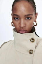 Light beige stand-collar trench coat close-up with brass-tone buttons