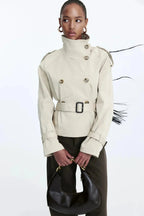 Light beige trench coat with stand collar, double-breasted buttons, and tied belt