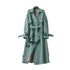 Women’s long trench coat with belt and lapels in green, plaid lining visible.
