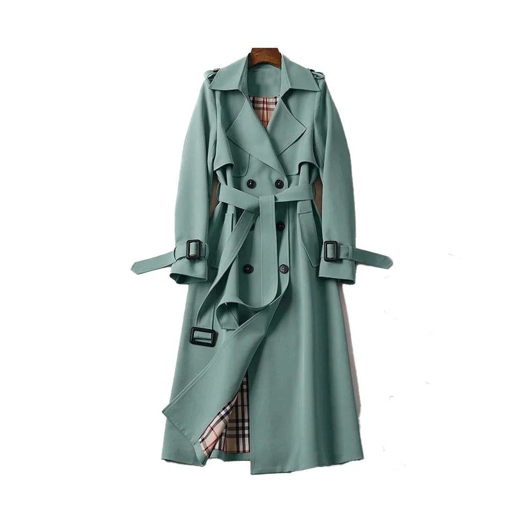 Women’s long trench coat with belt and lapels in green, plaid lining visible.