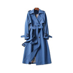 Women’s long trench coat with belt and lapels in blue, plaid lining at hem.
