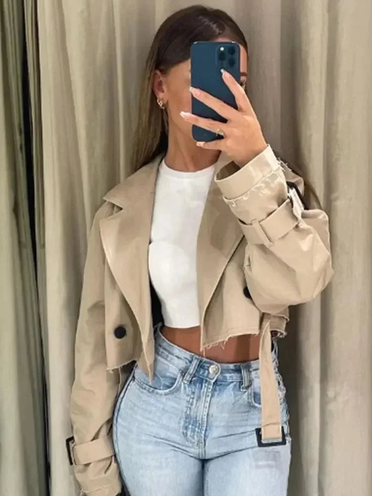 Women’s short light-brown trench coat worn over a white top, belted waist