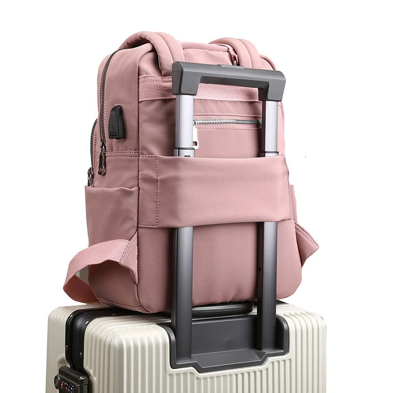 Pink water-resistant backpack with front pockets and side zippers, plus trolley strap