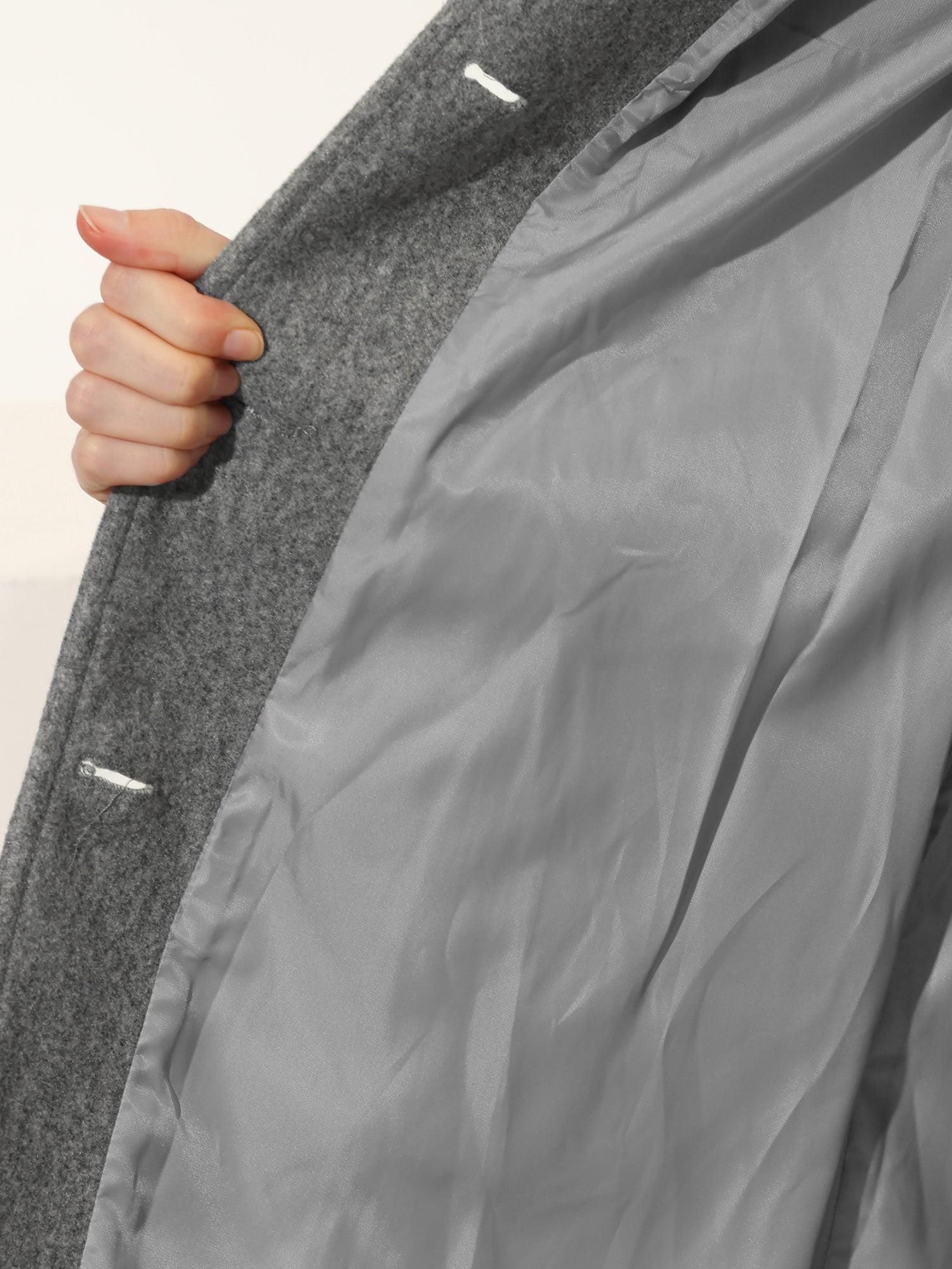 Grey wool-blend coat lining detail with inner fabric visible and white button studs