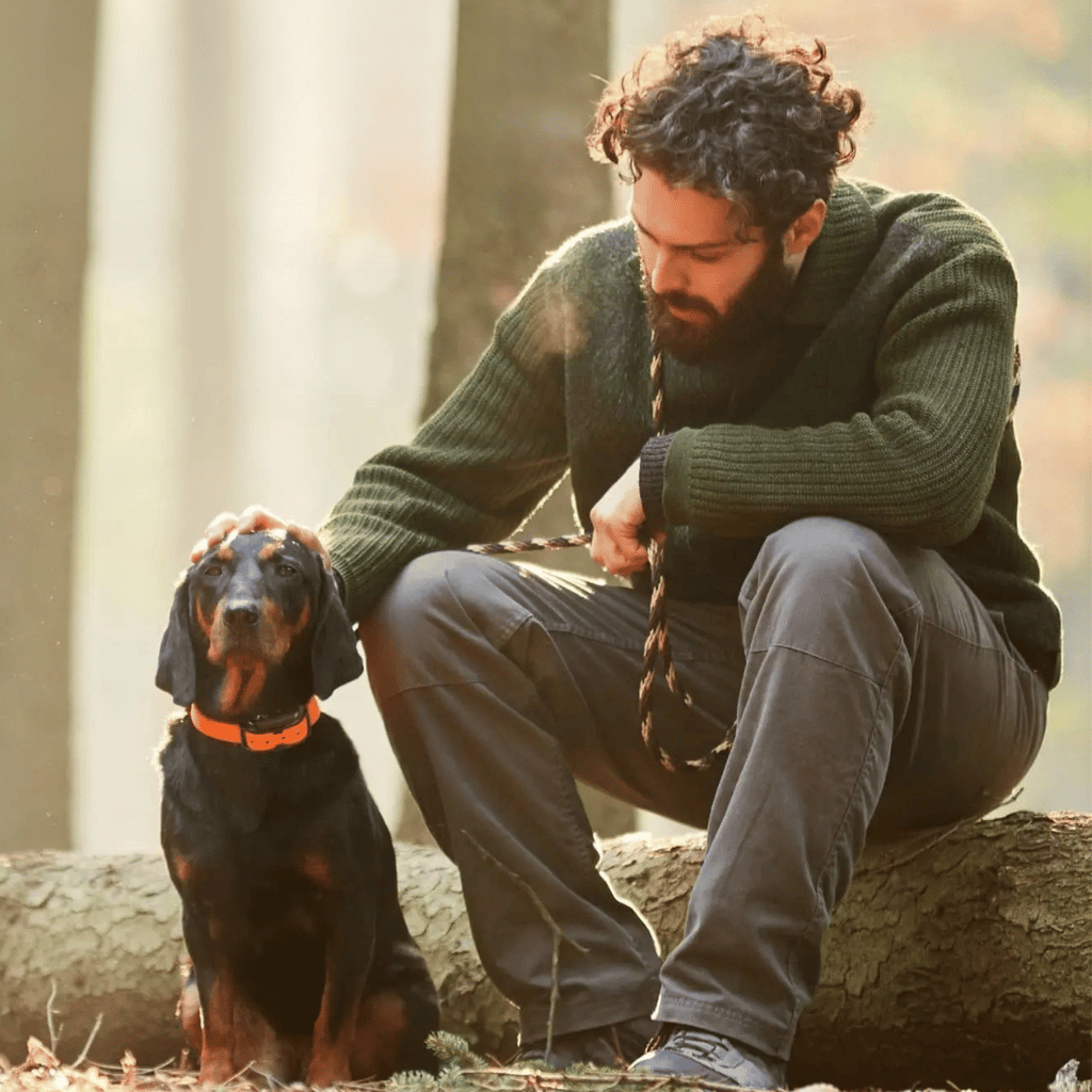 Orange dog training collar on a black dog beside a kneeling person