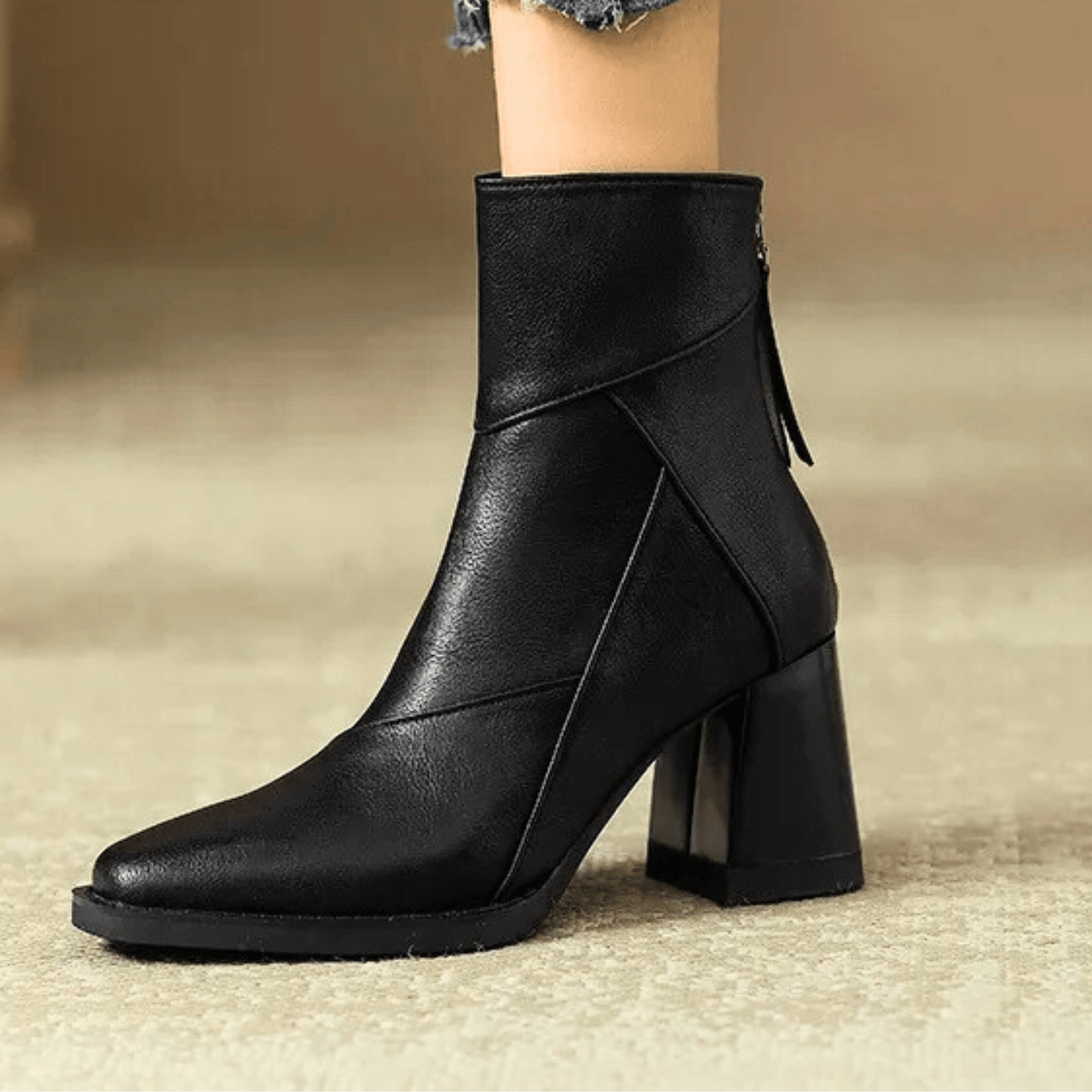 Black ankle boots with block heel and diagonal seam detail on smooth upper