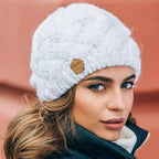 White knitted beanie hat with chunky texture and small brown brand patch