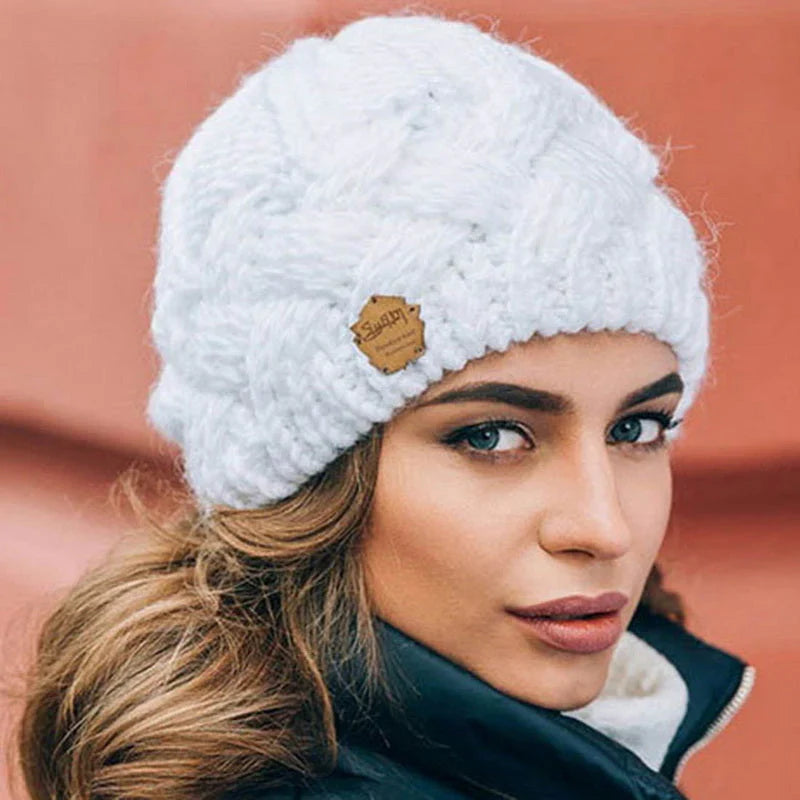 White knitted beanie hat with chunky texture and small brown brand patch